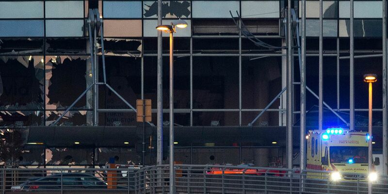 Ein Krankenwagen fährt an der zerstörten Fassade des Terminals des Flughafens Zaventem. (Archivbild) - Foto: Peter Dejong/AP/dpa