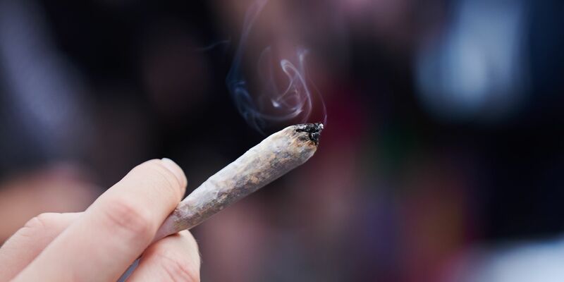 Eine Frau hält einen Joint in der Hand. - Foto: Annette Riedl/dpa