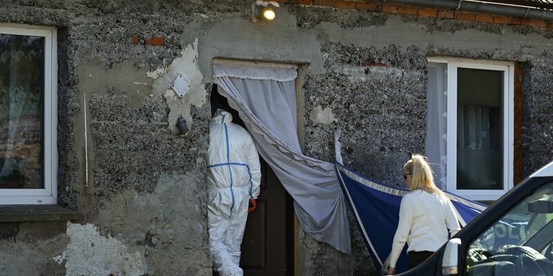 Ein Auto der Polizei steht während Ermittlungsarbeiten vor einem Familienhaus. - Foto: Adam Warzawa/PAP/dpa