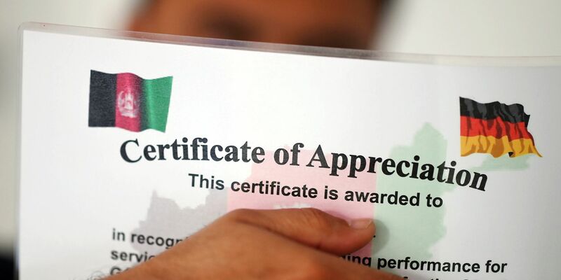 Ein geflüchteter Mann, der als afghanische Ortskraft tätig war, zeigt ein Zertifikat, das nach seinen eigenen Angaben die Zusammenarbeit mit der Bundeswehr in Afghanistan würdigt. - Foto: Uli Deck/dpa