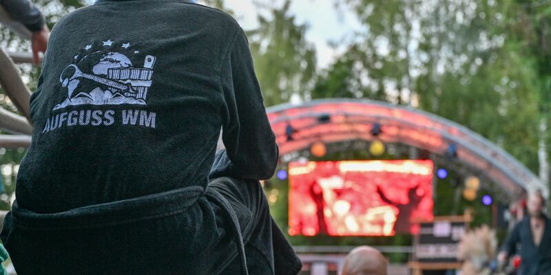 Ein Teilnehmer der Aufguss-Weltmeisterschaft 2023 verfolgt auf einer Videoleinwand einen Auftritt der Konkurenz. - Foto: Patrick Pleul/dpa