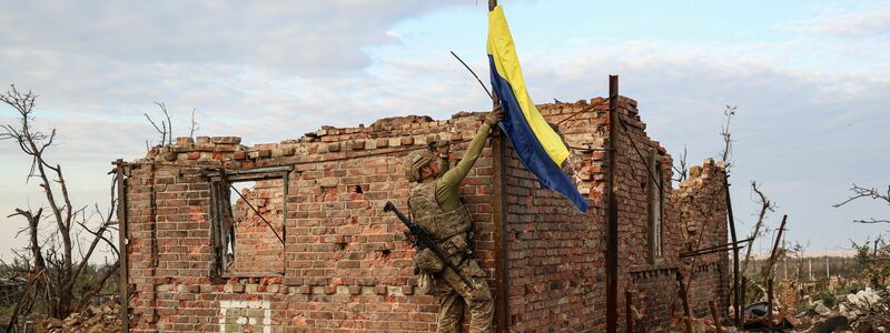Ein ukrainischer Kommandeur hisst die Nationalflagge als Symbol der Befreiung des Frontdorfes Andrijewka in der Region Donezk. - Foto: Alex Babenko/AP/dpa