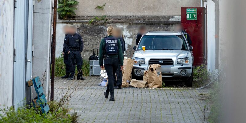 Polizistinnen und Polizisten stehen in einem Hinterhof in der Duisburger Innenstadt, auf dem Boden stehen Papiertüten mit Beweismitteln. - Foto: Christoph Reichwein/dpa