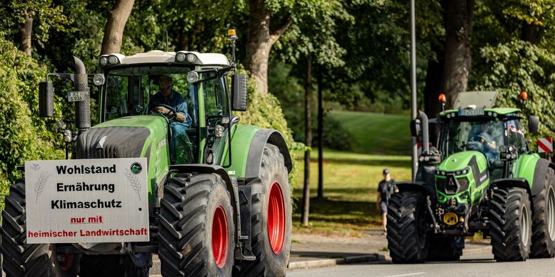 Ein Traktor mit einem Plakat mit der Aufschrift «Wohlstand Ernährung Klimaschutz nur mit heimischer Landwirtschaft» fährt zum Auftakt der Agrarministerkonferenz durch die Kieler Innenstadt. - Foto: Axel Heimken/dpa