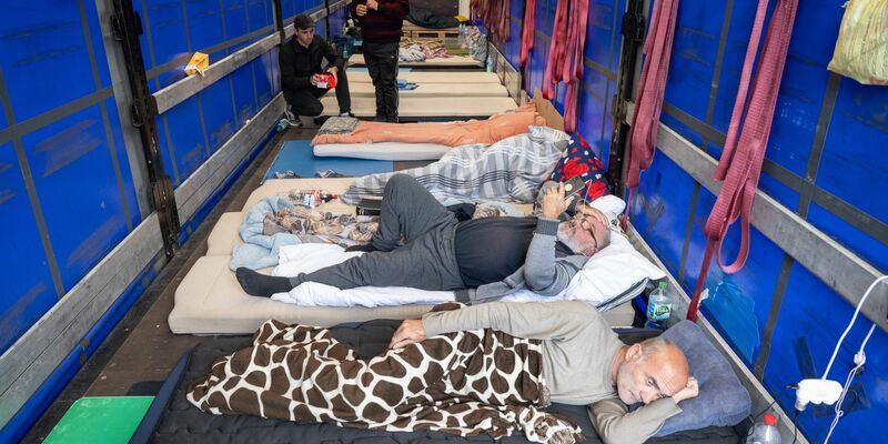 Trucker aus Georgien liegen auf einem Matratzenlager auf der Ladefläche eines Lkw. Sie sind in einen Hungerstreik getreten. - Foto: Boris Roessler/dpa