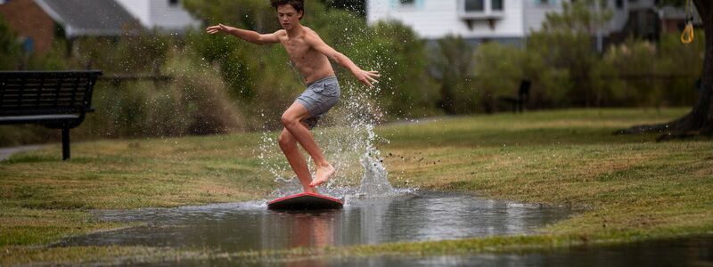 Ein Junge gleitet in Norfolk im US-Bundesstaat Virginia über das hohe Wasser des Lafayette River, während sich der Tropensturm «Ophelia» nähert. - Foto: Kendall Warner/The Virginian-Pilot/AP/dpa