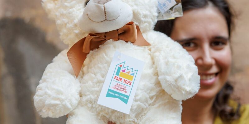 Eine Mitarbeiterin des Plüschtierherstellers Heunec präsentiert einen Stoffteddy, der mit dem Siegel der Fair Toys Organisation gekennzeichnet ist. - Foto: Daniel Karmann/dpa