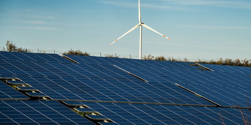 Ein Windrad steht auf einem Hügel einer großflächigen Solaranlage. - Foto: Frank Rumpenhorst/dpa