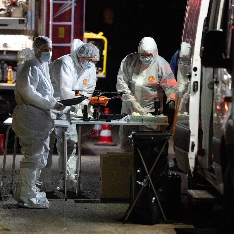 Mitarbeiter der Spurensicherung stehen nach dem Fund einer Frauenleiche an ihren Einsatzfahrzeugen. - Foto: Swen Pförtner/dpa