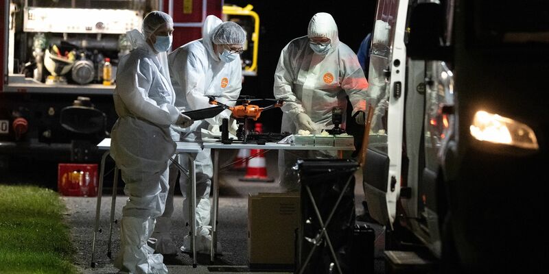 Mitarbeiter der Spurensicherung stehen nach dem Fund einer Frauenleiche an ihren Einsatzfahrzeugen. - Foto: Swen Pförtner/dpa