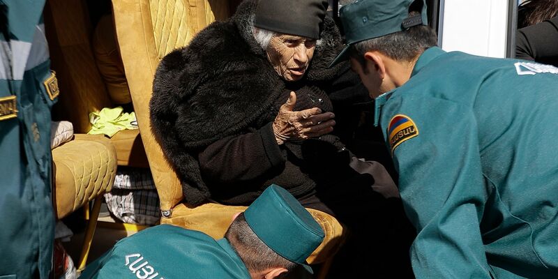 Mitarbeiter des armenischen Ministeriums für Notfallsituationen sprechen mit einer älteren armenischen Frau aus Berg-Karabach bei ihrer Ankunf in Goris. - Foto: Vasily Krestyaninov/AP/dpa