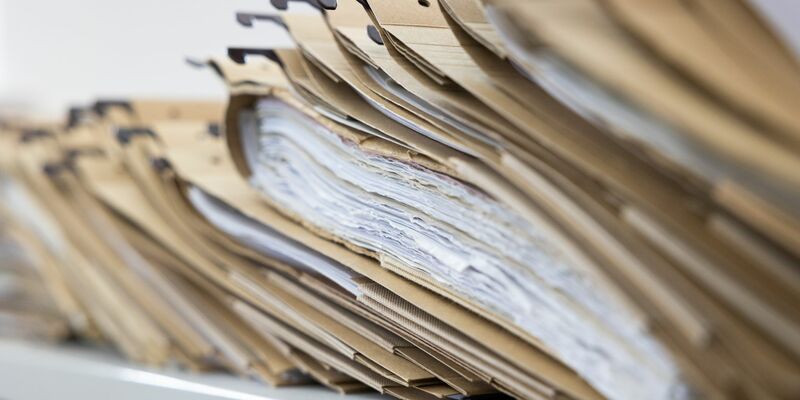 Zahlreiche Akten sind auf einem Schreibtisch ausgelegt. - Foto: Lando Hass/dpa