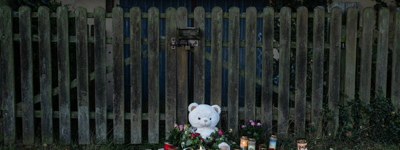 Kerzen, Blumen und ein großer Plüschteddy vor einem Zaun am Fundort der Leiche einer 14-Jährigen. - Foto: Swen Pförtner/dpa