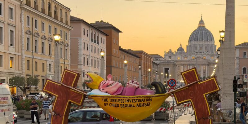 Einer Figur des Künstlers Jacques Tilly, die ironisch die Kirche für ihre Missbrauchsermittlungen kritisiert, steht in Rom in Sichtweite des Petersdoms. - Foto: Ricarda Hinz/dpa
