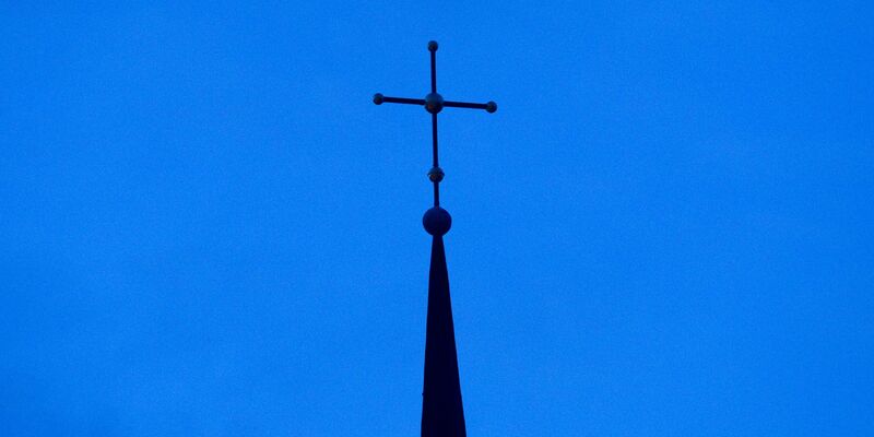 Kreuz einer evangelisch-lutherischen Kirche in der Abenddämmerung. - Foto: Friso Gentsch/dpa