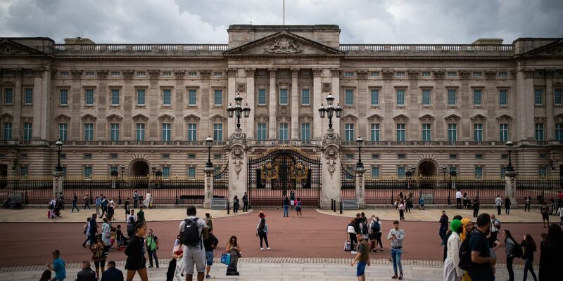 Touristen stehen vor den Toren vom Buckingham Palast in London. - Foto: Aaron Chown/PA Archive/dpa