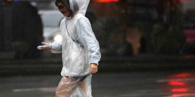Eine Frau läuft bei Regen und Wind durch Taipeh. - Foto: ChiangYing-ying/AP/dpa