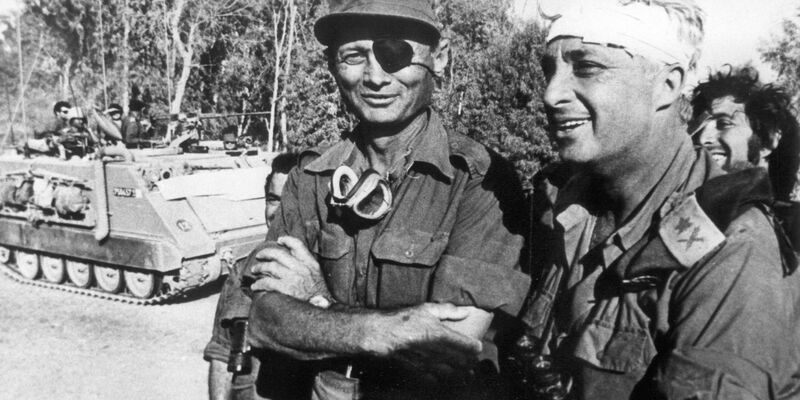 Der damalige israelische Verteidigungsminister und General Mosche Dajan (l.) mit dem damaligen Generalmajor Ariel Scharon, der einen Kopfverband trägt, aufgenommen im Oktober 1973 auf der ägyptischen Seite des Suezkanals während des 4. israelisch-arabischen Krieges. - Foto: UPI/dpa