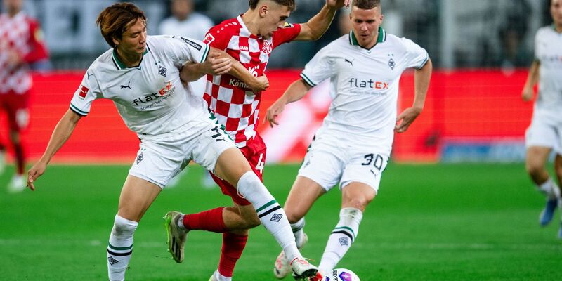 Nach einem harten Kampf trennen sich Gladbachs Ko Itakura (l) und der Mainzer Brajan Gruda (M)und ihre Teams 1:1. - Foto: Marius Becker/dpa