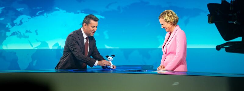Jens Riewa (l-r) schenkt Caren Miosga am Ende ihrer letzten Sendung eine Snoopy-Figur. - Foto: Jonas Walzberg/dpa
