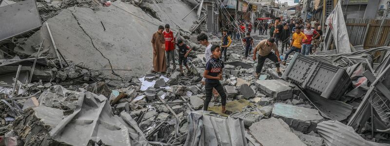Palästinenser laufen nach einem israelischen Luftangriff im Gazastreifen zwischen den Trümmern eines zerstörten Gebäudes umher. - Foto: Abed Rahim Khatib/dpa