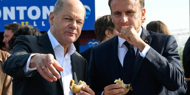 Bundeskanzler Olaf Scholz (SPD) und Frankreichs Präsident Emmanuel Macron (r) essen an der Elbe in Hamburg-Blankenese Fischbrötchen. - Foto: Fabian Bimmer/Reuters/Pool/dpa