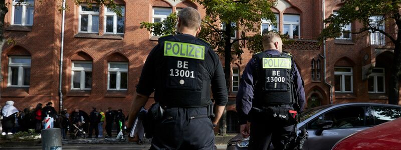 Polizisten stehen vor der Schule in Berlin-Neukölln. - Foto: Joerg Carstensen/dpa