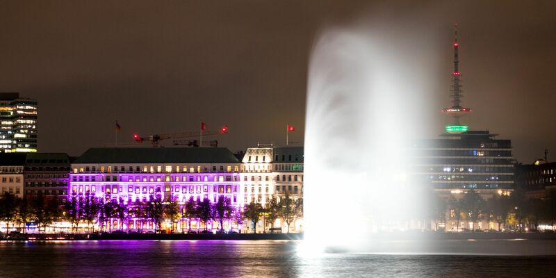 Das Hotel «Vier Jahreszeiten» an der Binnenalster in Hamburg ist während einer Aktion der Organisation «Plan International» zum Weltmädchentag beleuchtet. - Foto: Daniel Bockwoldt/dpa
