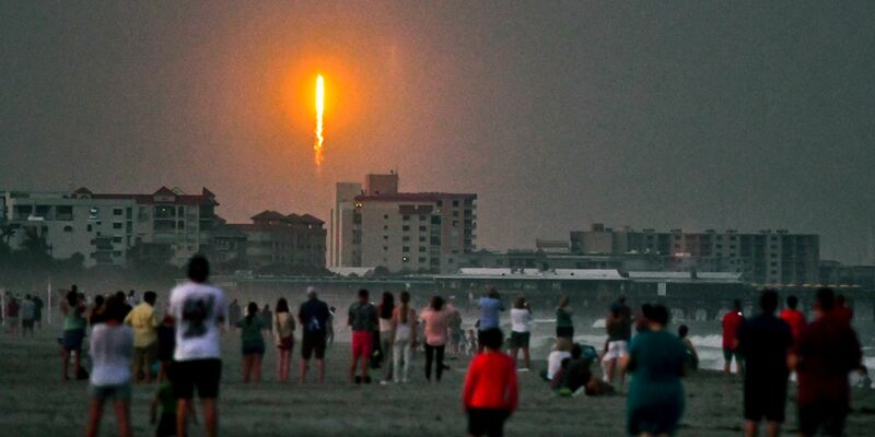 Menschen beobachten am Cocoa Beach im US-Bundesstaat Florida, wie die SpaceX-Rakete in Cape Canaveral abhebt. - Foto: Malcolm Denemark/Florida Today/AP/dpa