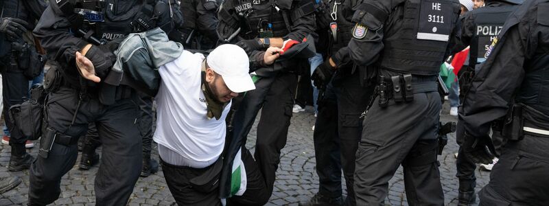 Polizisten halten am Rande der Pro-Palästina-Demo in Frankfurt am Main einen Teilnehmer fest. - Foto: Boris Roessler/dpa