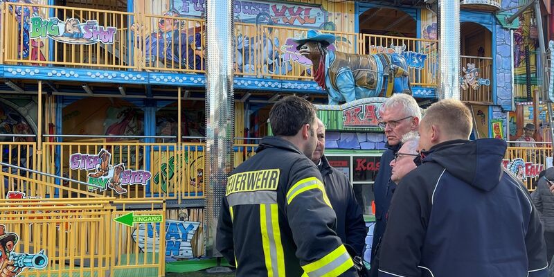 Feuerwehrleute und Polizisten stehen vor dem Funhouse auf dem Pollhansmarkt in Schloß Holte-Stukenbrock. - Foto: Christian Müller/Westfalennews/dpa