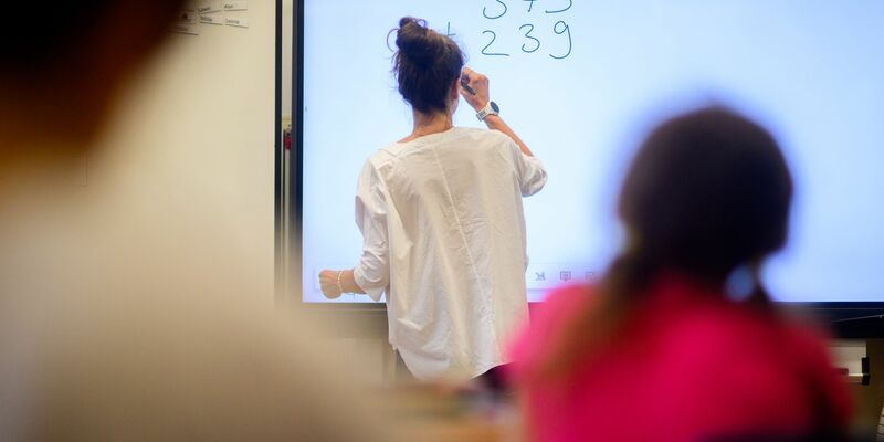 Eine Lehrerin schreibt eine Mathematikaufgabe auf eine digitale Schultafel im Klassenraum einer 4. Klasse einer Grundschule. - Foto: Julian Stratenschulte/dpa