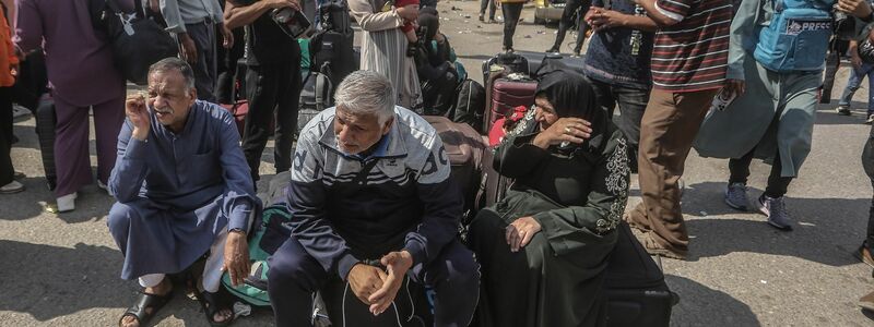 Palästinenser, einige mit ausländischen Pässen, warten am Grenzübergang Rafah auf Hilfe und eine mögliche Einreise nach Ägypten. - Foto: Mohammed Talatene/dpa