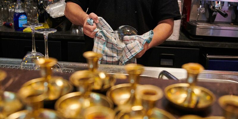 Ein Mitarbeiter eines mexikanischen Restaurants in Prenzlauer Berg poliert die Weingläser. - Foto: Annette Riedl/dpa