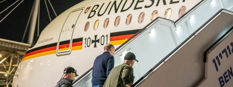 Bodyguards bringen Bundeskanzler Olaf Scholz nach dem Luftalarm in den Regierungs-Airbus. - Foto: Michael Kappeler/dpa Pool/dpa