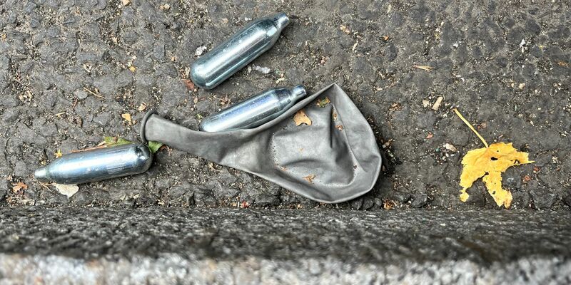 Auf einer Straße im Londoner Stadtteil Bethnal Green liegen mehrere Gaspatronen und ein Luftballon. - Foto: Julia Kilian/dpa