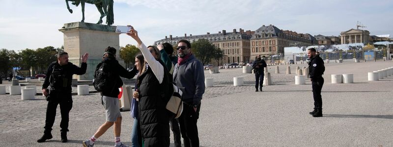Touristen warten, während französische Polizisten das Schloss von Versailles nach einem Sicherheitsalarm bewachen. - Foto: Christophe Ena/AP/dpa