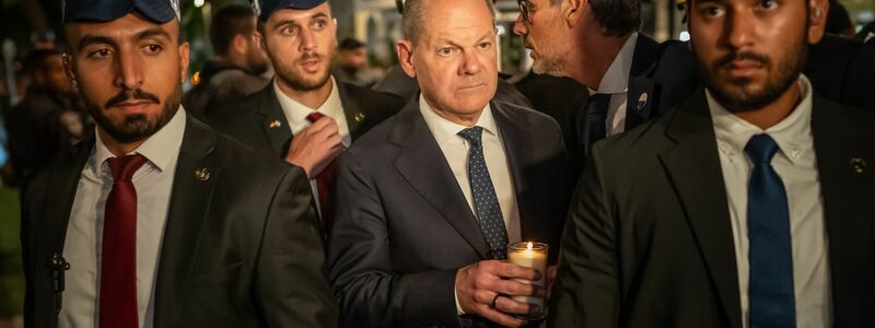 Bundeskanzler Olaf Scholz, umringt von Bodyguards, bei seinem Solidaritätsbesuch in Israel mit einer Kerze in der Hand am Dizengoff Square im Zentrum von Tel Aviv. - Foto: Michael Kappeler/dpa Pool/dpa