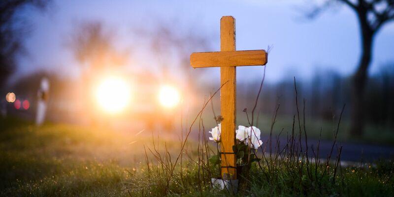 Ein Kreuz und Blumen zum Gedenken an ein 21-jähriges Opfer eines Verkehrsunfalls im Landkreis Hildesheim. - Foto: Julian Stratenschulte/dpa