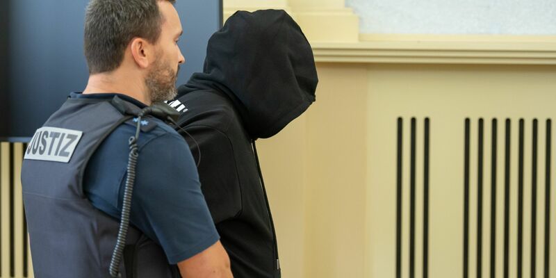 Der Angeklagte (r) wird vor Prozessbeginn in den Gerichtssaal gebracht. Gegen ihn wurde eine lebenlange Haftstrafe verhängt. - Foto: Silas Stein/dpa