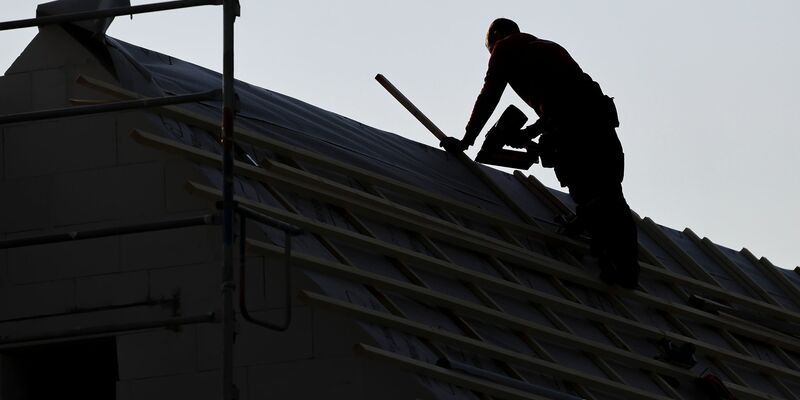 Ein Dachdecker arbeitet auf einem Einfamilienhaus. - Foto: Jan Woitas/dpa