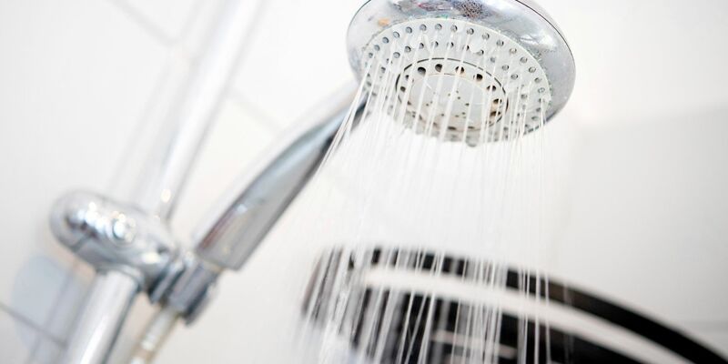 Ein Duschkopf hängt in einer Dusche in einem Badezimmer. - Foto: Hauke-Christian Dittrich/dpa