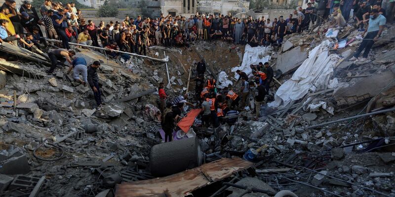 Palästinenser versammeln sich vor den Überresten eines zerstörten Hauses in Gaza-Stadt. - Foto: Abed Khaled/AP/dpa