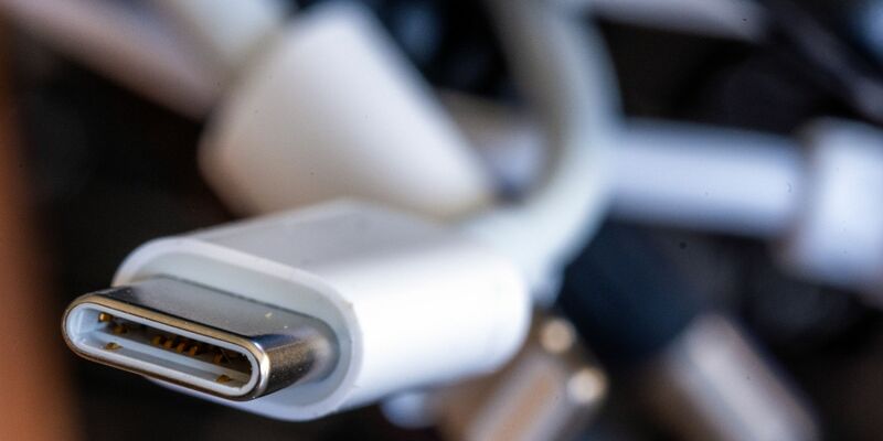Ein Ladekabel mit USB-C-Stecker liegt neben einem Bündel unterschiedlicher Anschlusskabel. - Foto: Jens Büttner/dpa