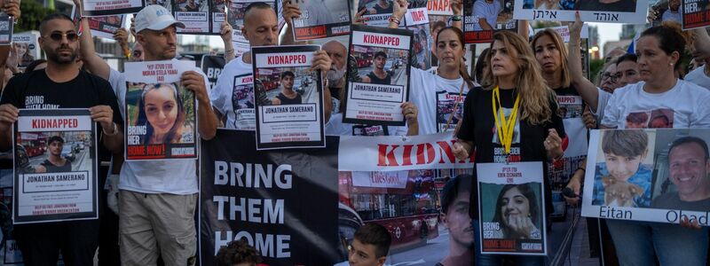Angehörige von Hamas-Geiseln mit Bildern der Entführten. - Foto: Ohad Zwigenberg/AP/dpa