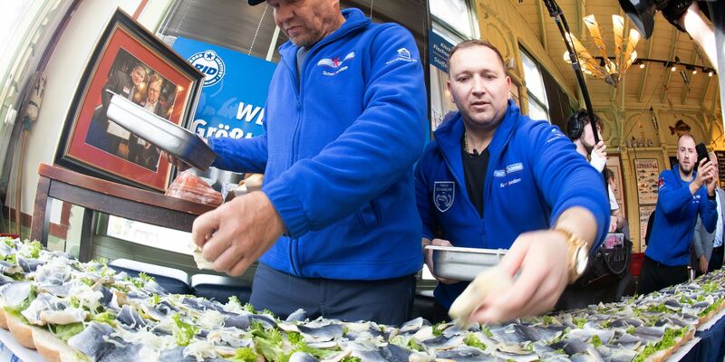 Axel Schulz, ehemalige Profiboxer (l-r), und André Domke, Fischsommelier und -händler, belegen das gigantische Fischbrötchen mit Salat, Fisch und Zwiebeln. - Foto: Stefan Sauer/dpa