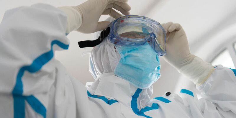 Ein Mitarbeiter des Gesundheitswesens legt im Hafen von Fuyuan seine Schutzkleidung an. Die Welt ist schlecht auf eine mögliche neue Gesundheitskrise vorbereitet. - Foto: Xie Jianfei/XinHua/dpa