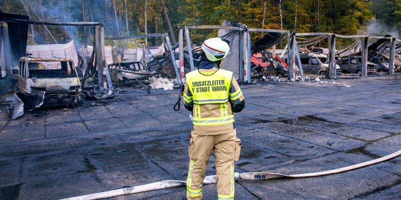 Feuerwehrleute löschen letzte Brandherde nach einem Feuer auf dem Gelände der Feuerwehr in Warin. - Foto: Jens Büttner/dpa