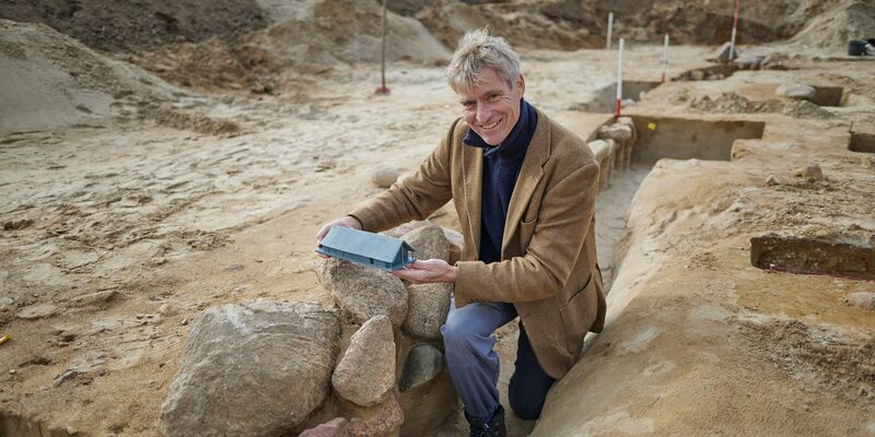 Der Grabungsleiter Immo Heske zeigt ein Modell der Versammlungshalle. - Foto: Joerg Carstensen/dpa