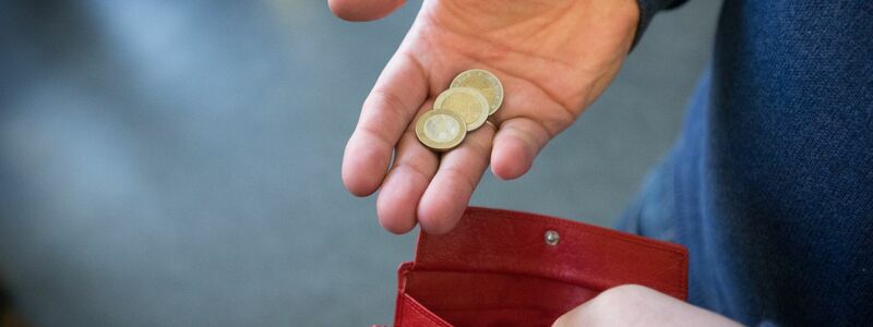 ILLUSTRATIOMünzen im Wert von fünf Euro liegen in einer Hand über einem Portemonnaie. - Foto: Friso Gentsch/dpa
